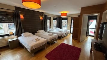 Ein Hotelzimmer mit drei Betten, einem roten Teppich und Holzboden.