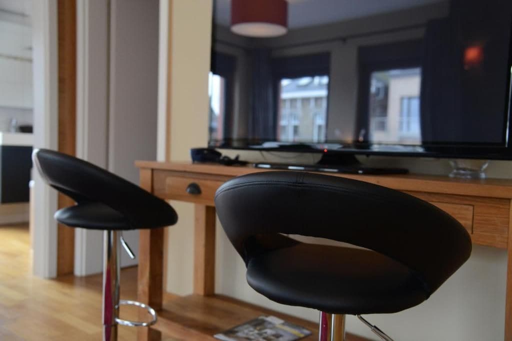 Una cocina moderna con encimera de madera, una silla negra y un televisor.