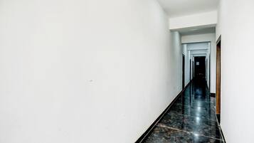 A long, narrow hallway with white walls and a black marble floor.
