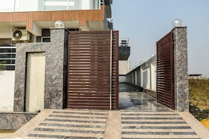 Uma entrada protegida por grades com um caminho de mármore que leva a um edifício de design moderno.