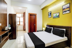A hotel room with a bed, bedside table, lamp, and a view of the hallway. - Hotel O Galaxy inn (Noida)