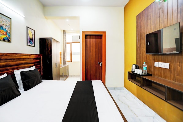 Quarto de hotel com cama, televisão, armário de madeira e banheiro visível através de uma porta aberta.