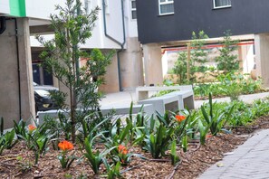 A garden area with a small tree, orange flowers, and a concrete bench.