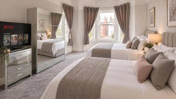 A hotel room with two beds, a TV, and a large window.