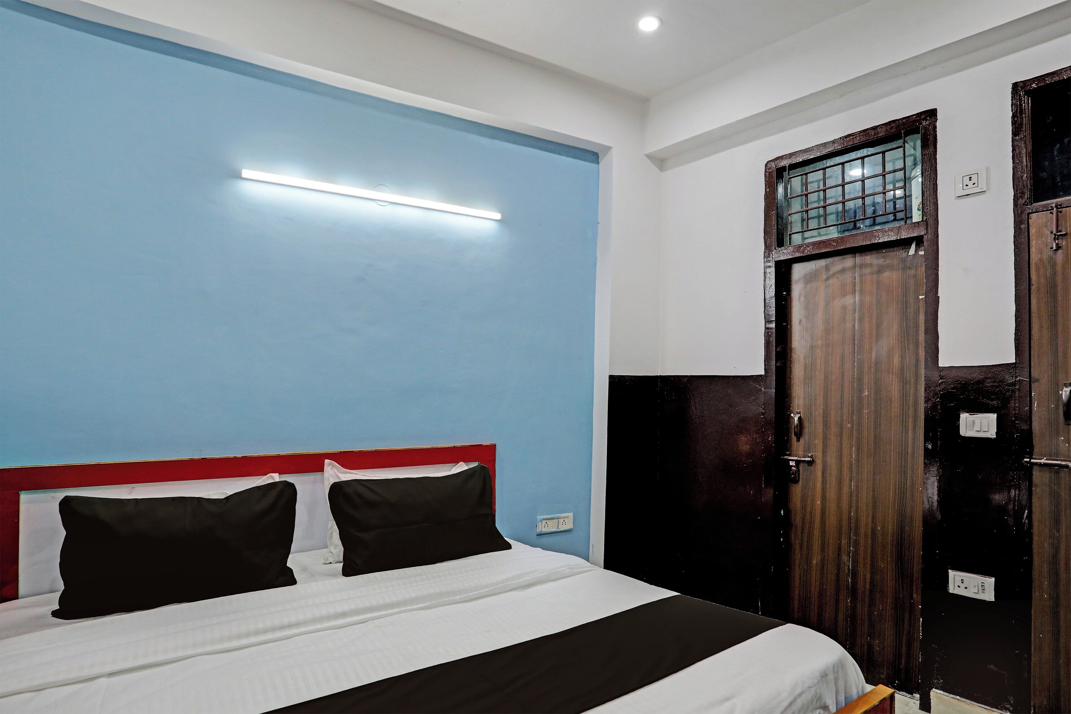 Una habitación con una cama, una puerta y una lámpara.