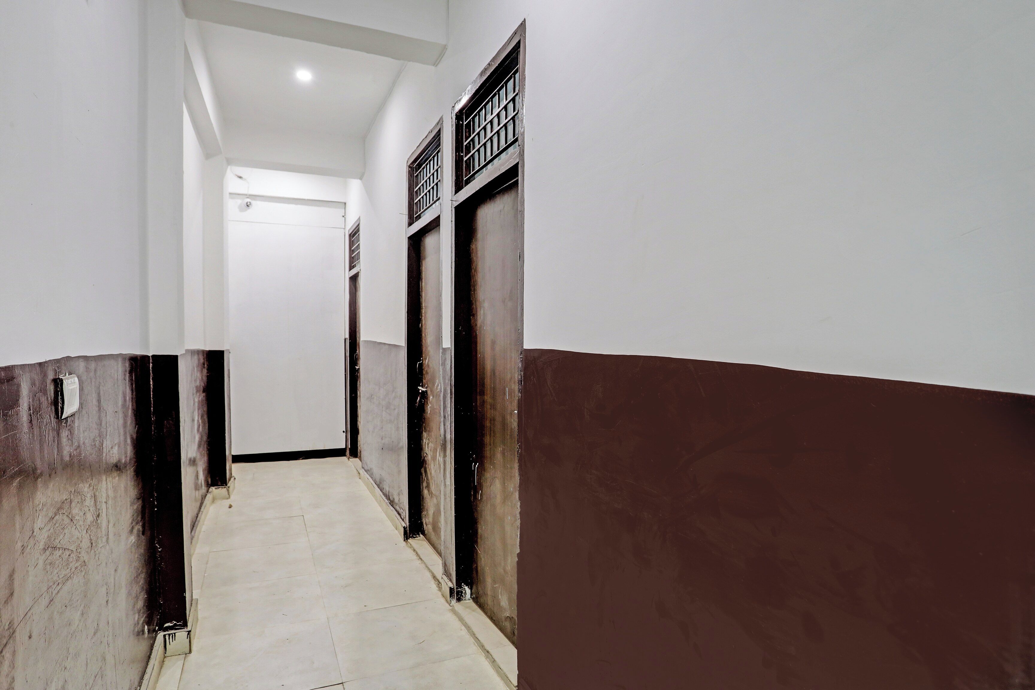 A corridor with a tiled floor leading to a door with a metal grille.