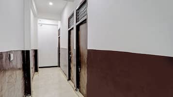 A corridor with a tiled floor leading to a door with a metal grille.