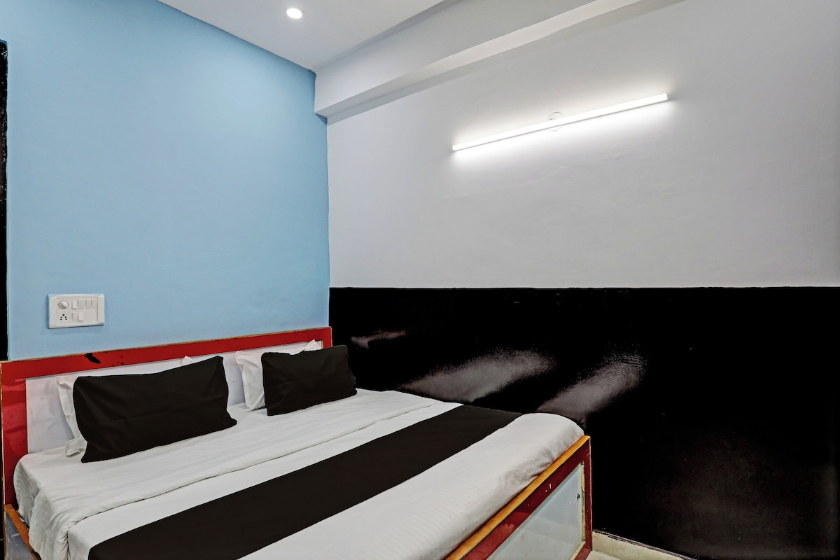 A bedroom with a bed, a wall socket, and a ceiling light fixture.