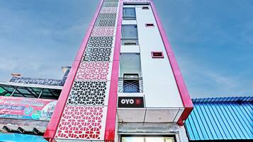 A hotel with a vertical facade featuring a series of windows and decorative panels.