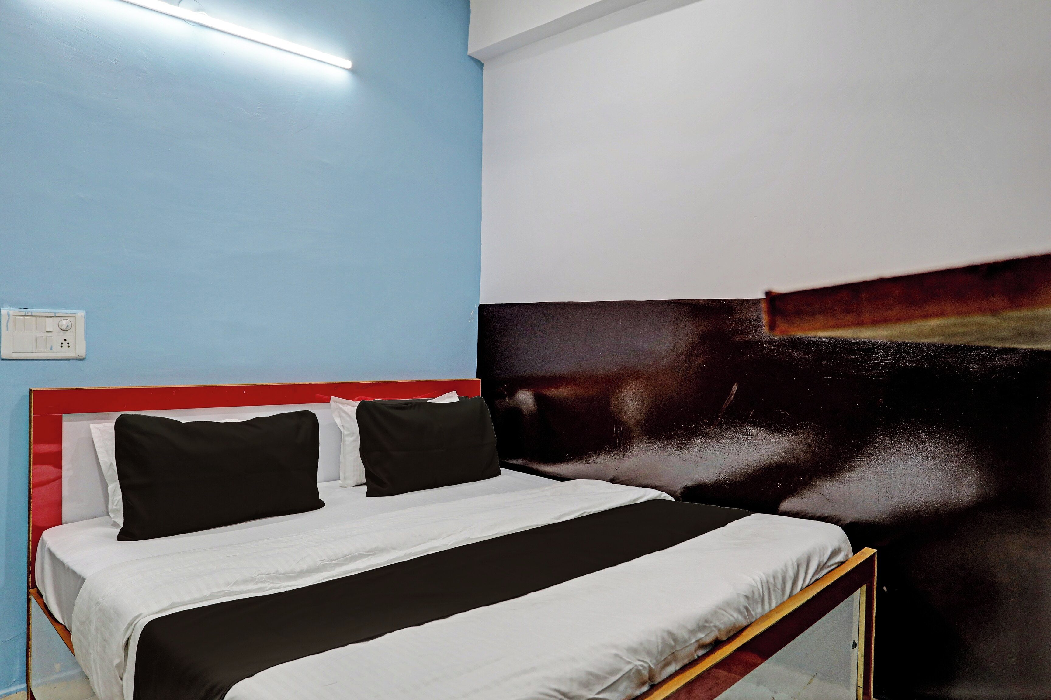 A bed with a black and white striped bedspread, a red headboard, and a wall with a large abstract painting.
