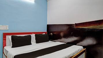 A bed with a black and white striped bedspread, a red headboard, and a wall with a large abstract painting.