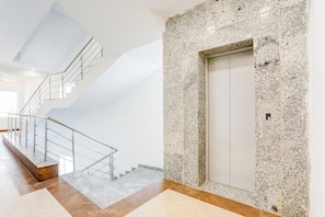 Un intérieur moderne avec un escalier, un mur en marbre et un ascenseur.