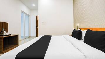 Een hotelkamer met een bed, een houten nachtkastje, een waterkoker en een behangen muur.