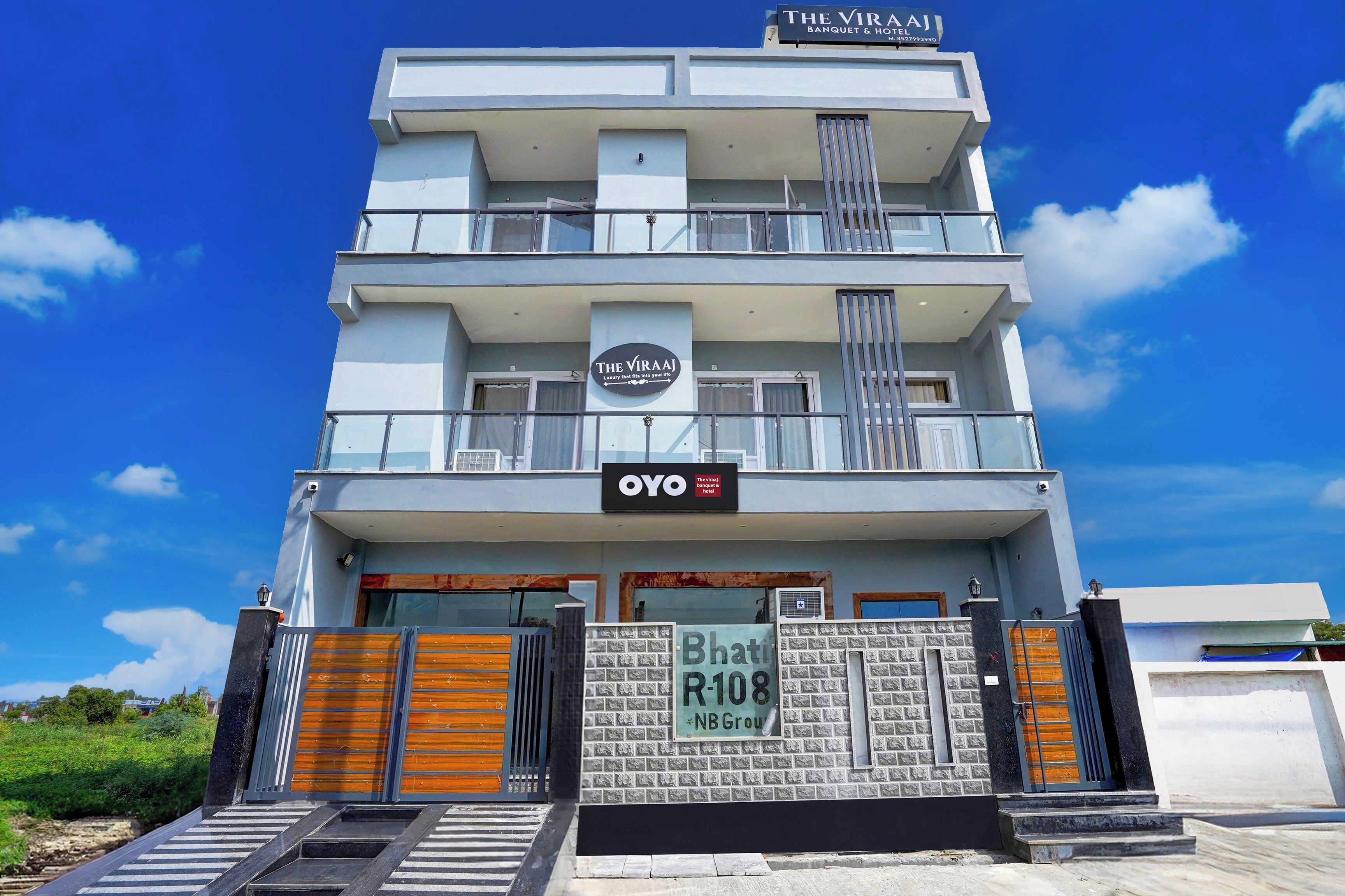 A modern hotel with a sign for 'The Viraj Banquet & Hotel' and a 'NB Group' sign below.
