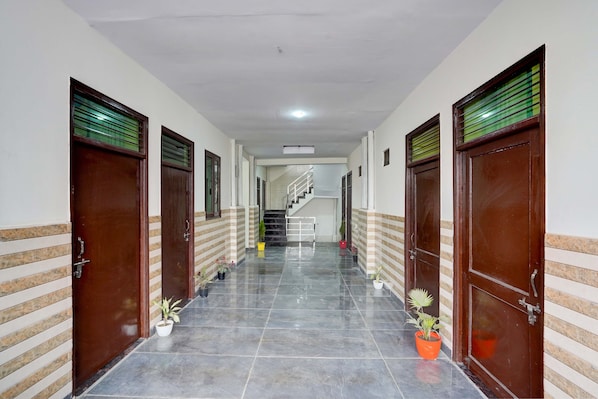 A corridor with doors on both sides, a tiled floor, and a staircase in the distance.
