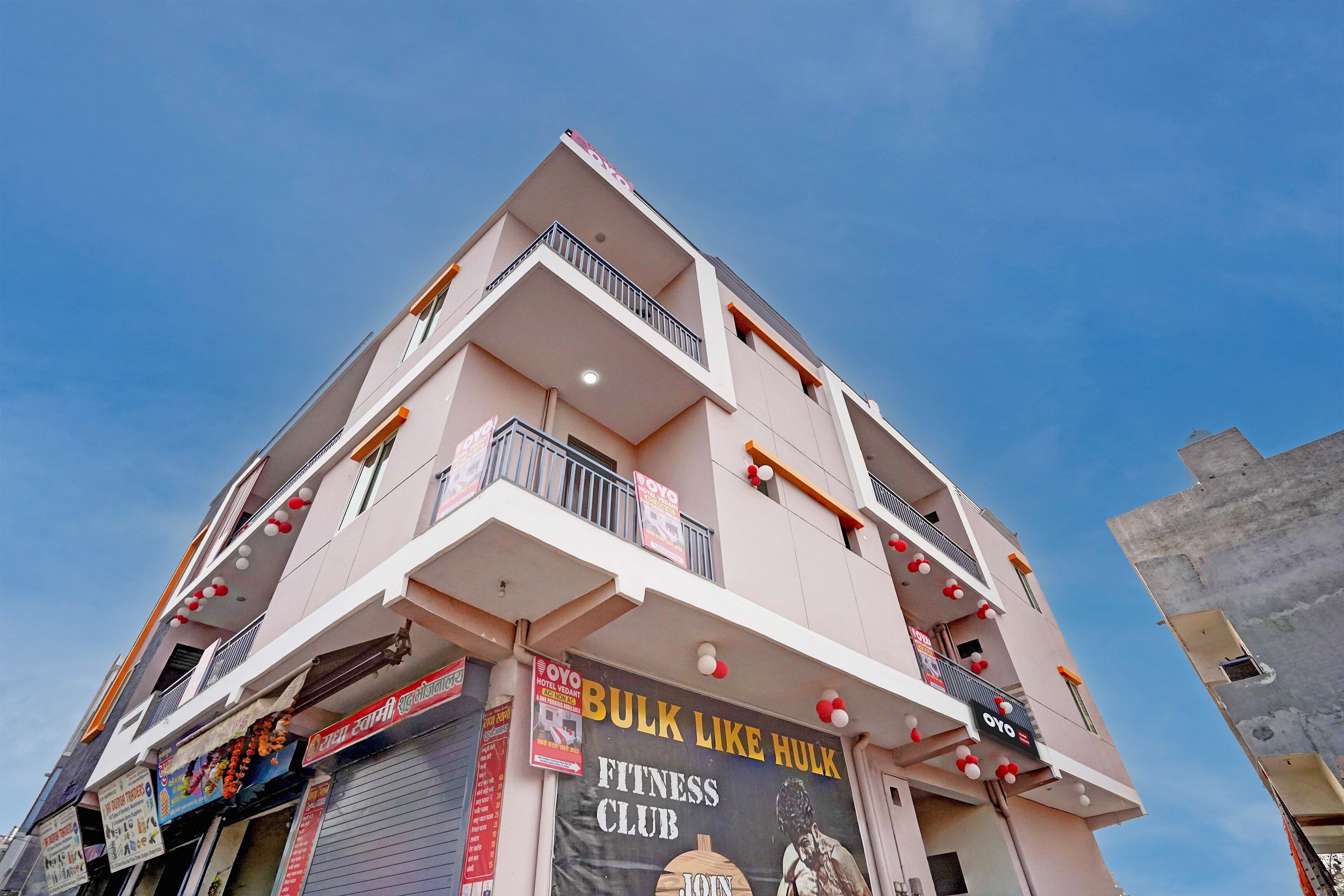 A multi-story building with balconies, a sign for a fitness club, and various advertisements.