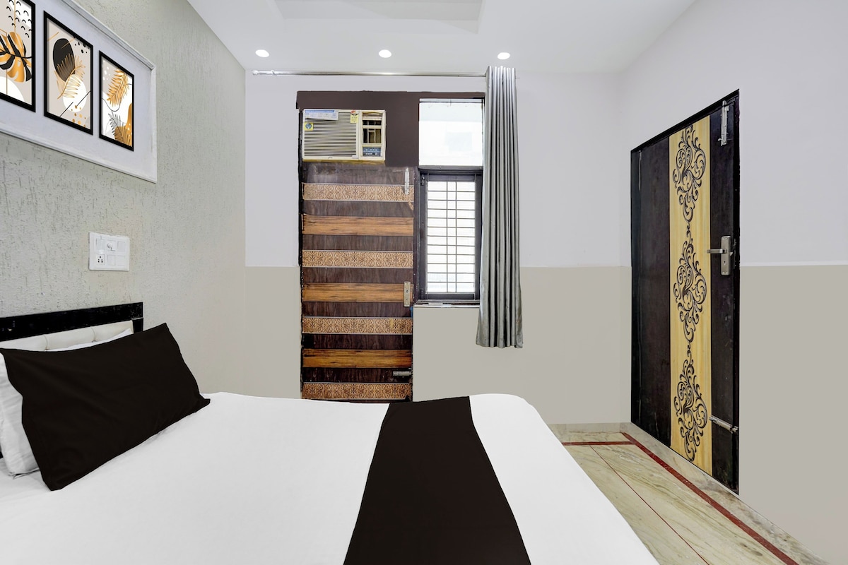 Une chambre à coucher comprenant un lit, une armoire, une fenêtre avec des rideaux et un mur orné de tableaux encadrés.