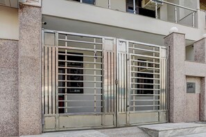 A metal gate with vertical bars, a stone wall, and a small plaque with text. - Hotel O N Nature Green (Noida)