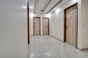 A corridor with three wooden doors, each marked with a number. The floor is tiled with a marble pattern. - Townhouse Oak Sector 63 A Noida (Noida)