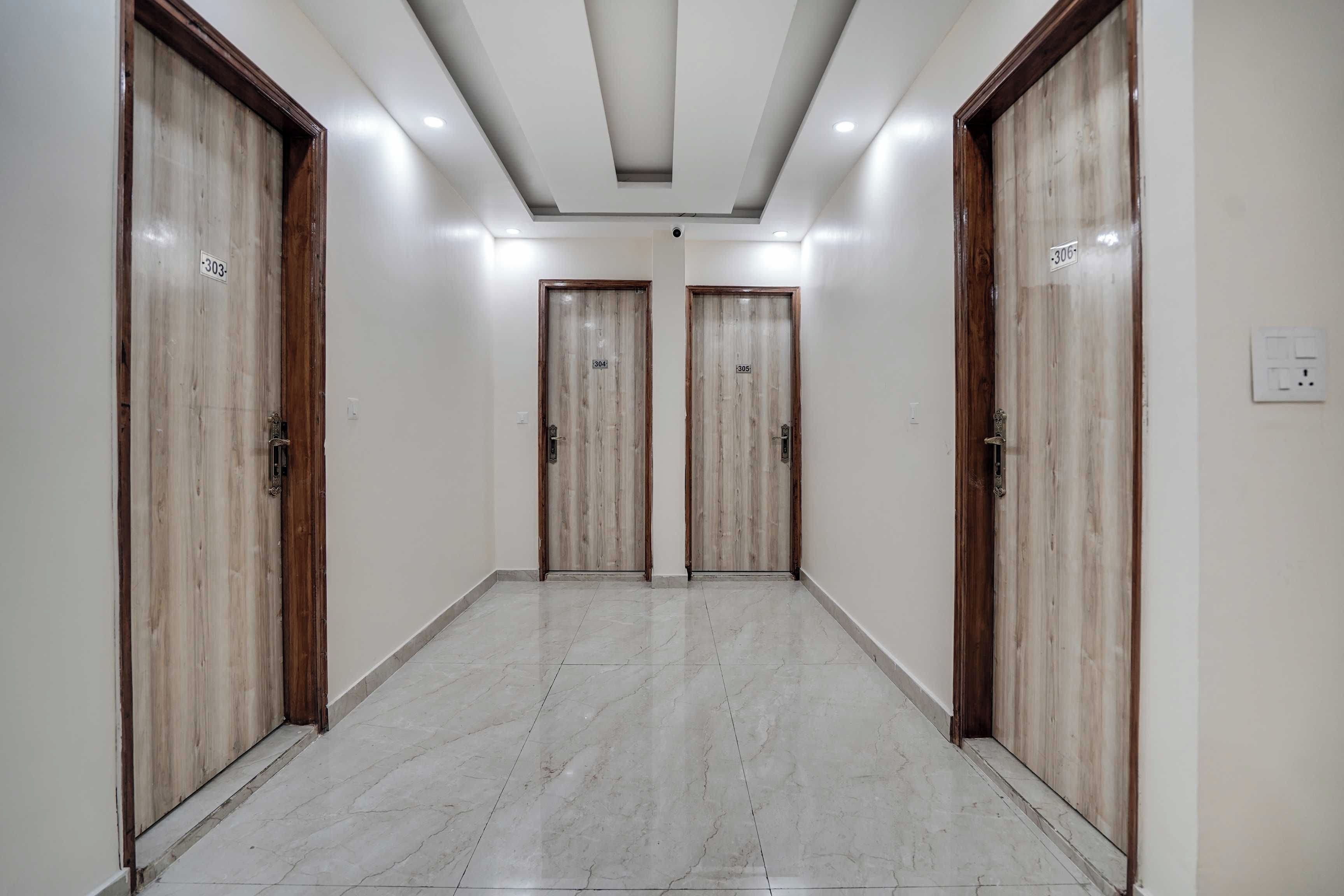 Un pasillo con tres puertas de madera, cada una marcada con un número. El suelo está cubierto de baldosas y las paredes son lisas.