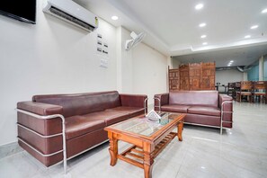A modern lobby with leather sofas, a glass coffee table, and a decorative wooden partition. - Townhouse Oak Sector 63 A Noida (Noida)