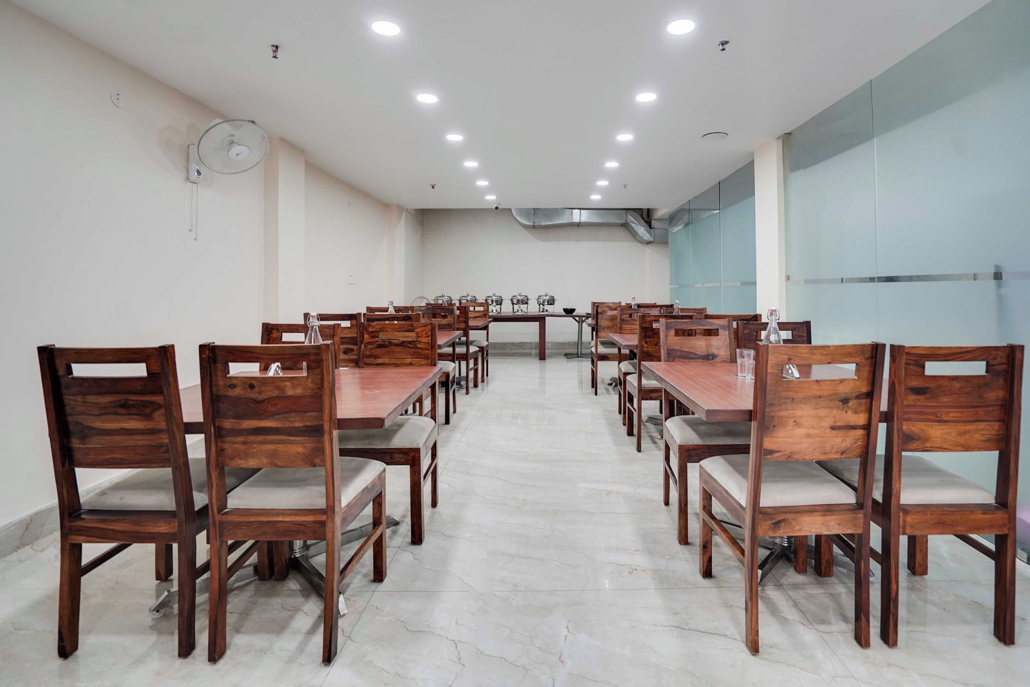 Un salón de conferencias con mesas y sillas de madera, un reloj en la pared y un panel de vidrio en un lateral.