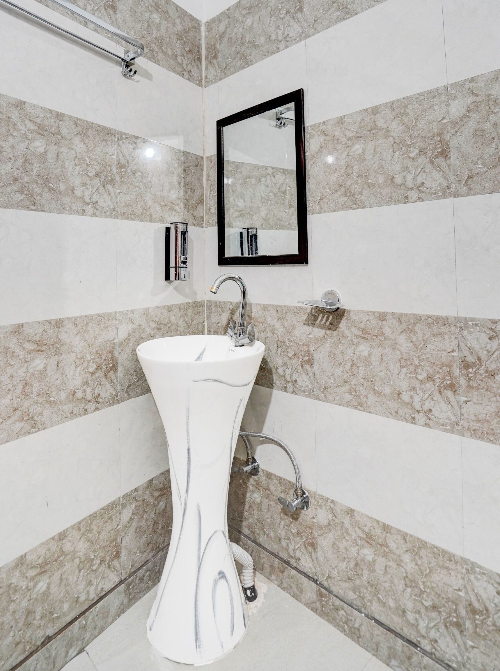 Un baño con lavamanos de pedestal blanco, un espejo y una ducha.