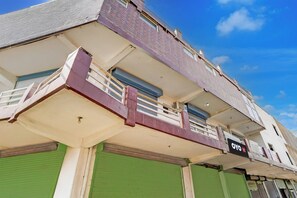 Un edifici de diverses plantes amb un terrat pla, un balcó al segon pis i un senyal que indica un hotel.