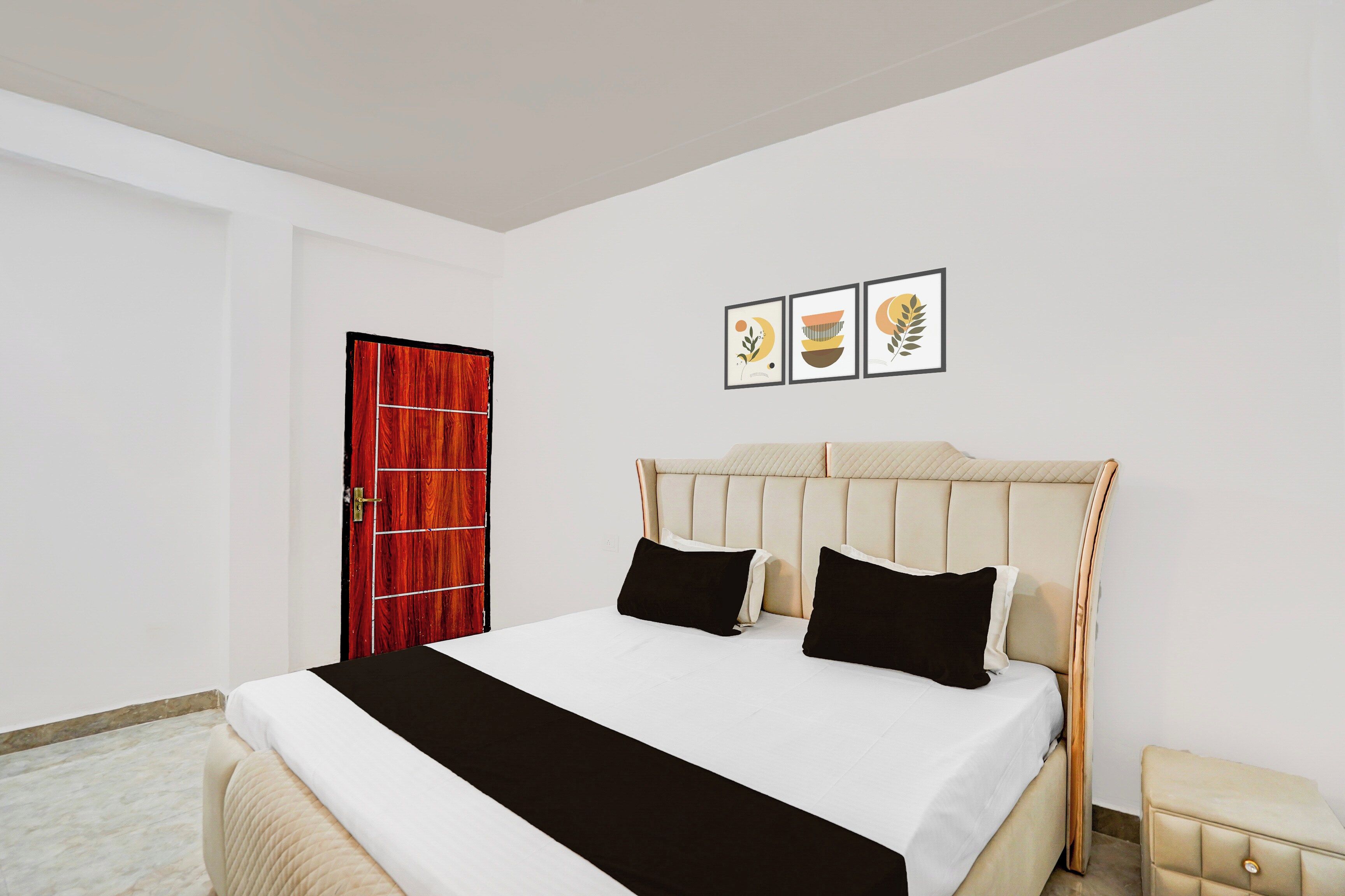 Una habitación de hotel con una cama, una puerta roja y tres cuadros en la pared.