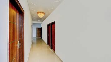 A hallway with wooden doors, a chandelier, and a tiled floor.