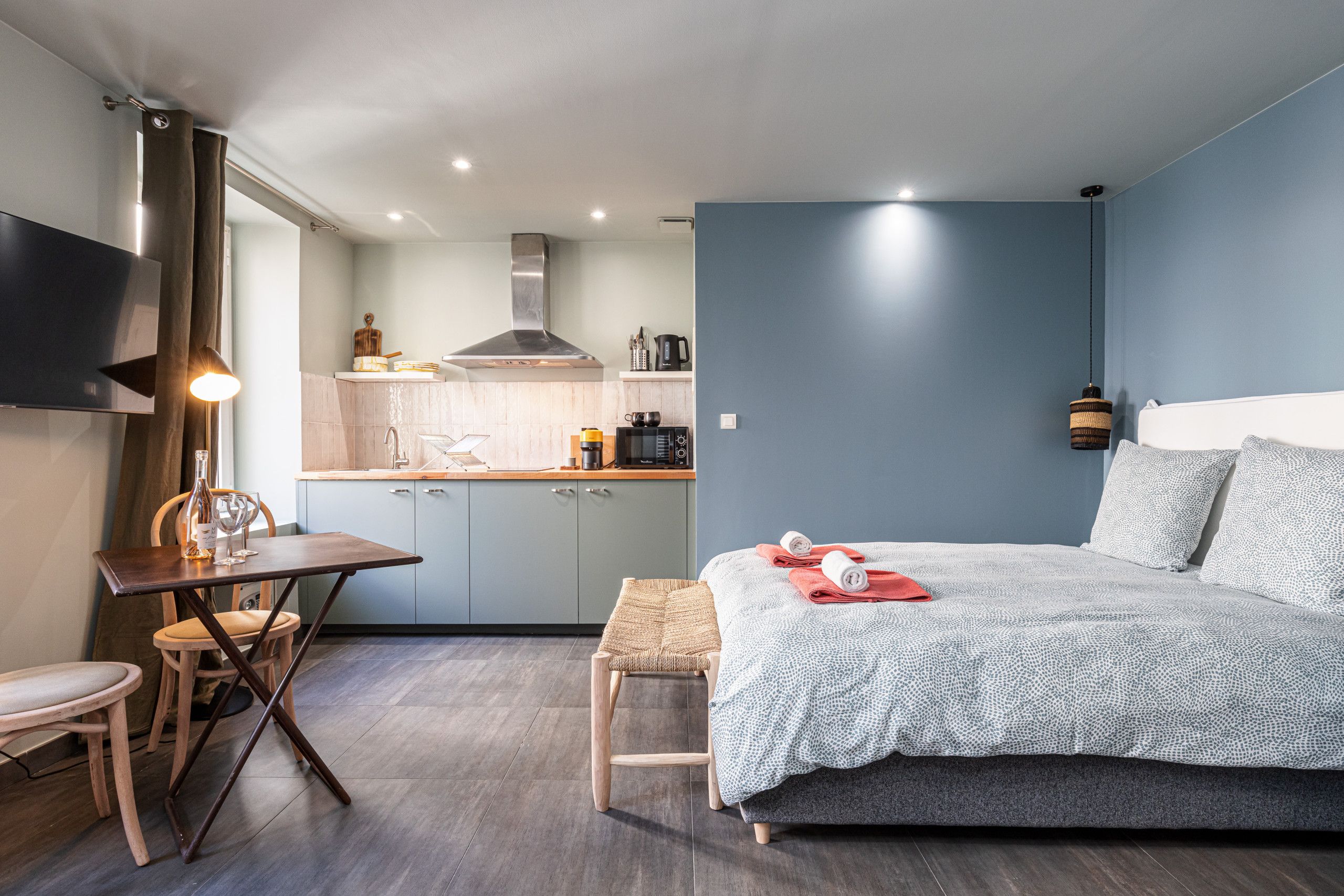 Een knus slaapkamer met een bed, nachtkastje en een klein zithoekje.