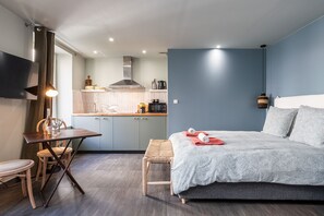 Een knus slaapkamer met een bed, nachtkastje en een klein zithoekje.