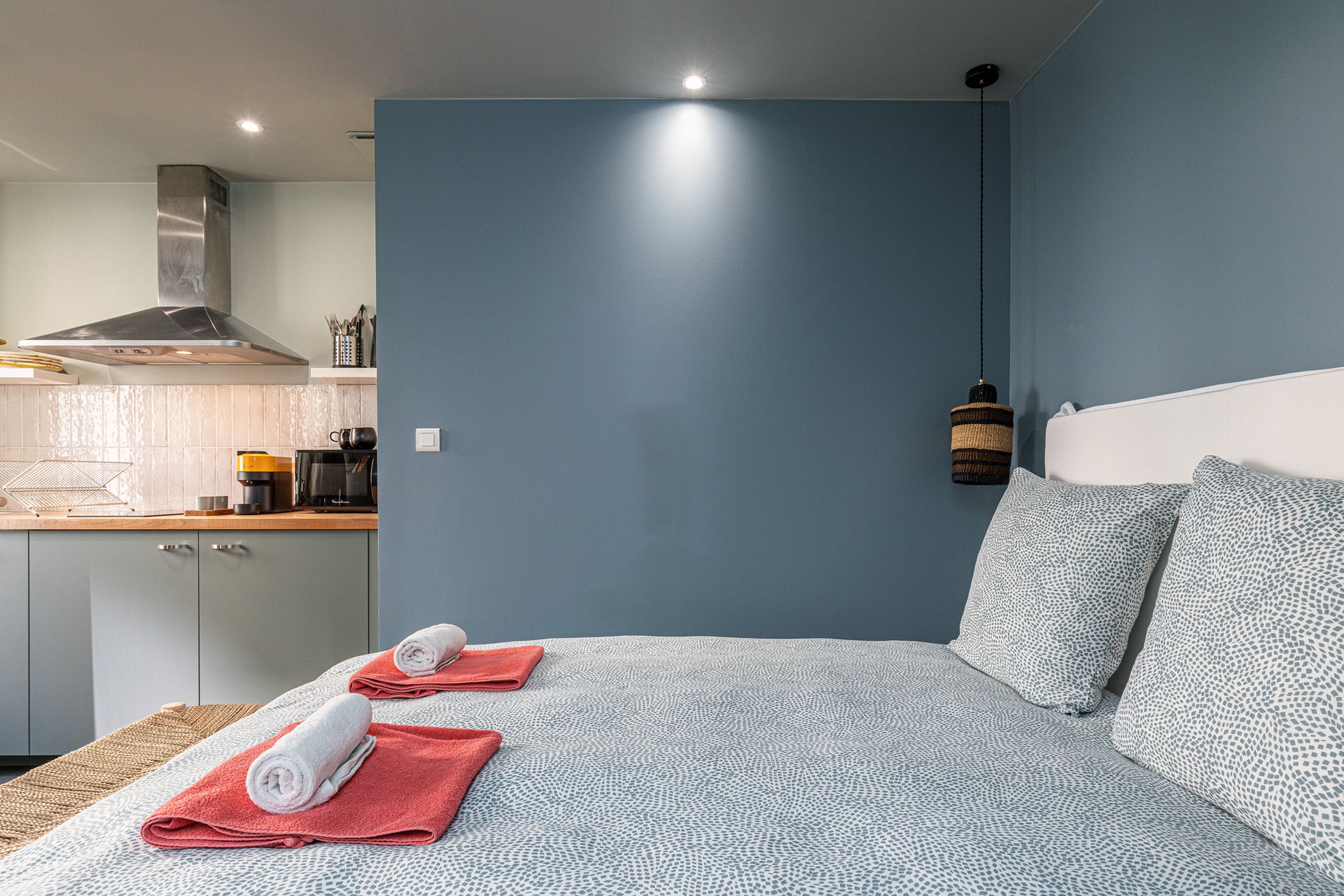 Een slaapkamer met een bed, kussens en een opgerolde handdoek.
