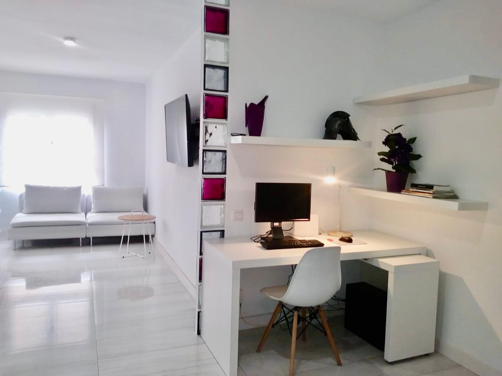 A modern office space with a desk, chair, computer, and shelves.