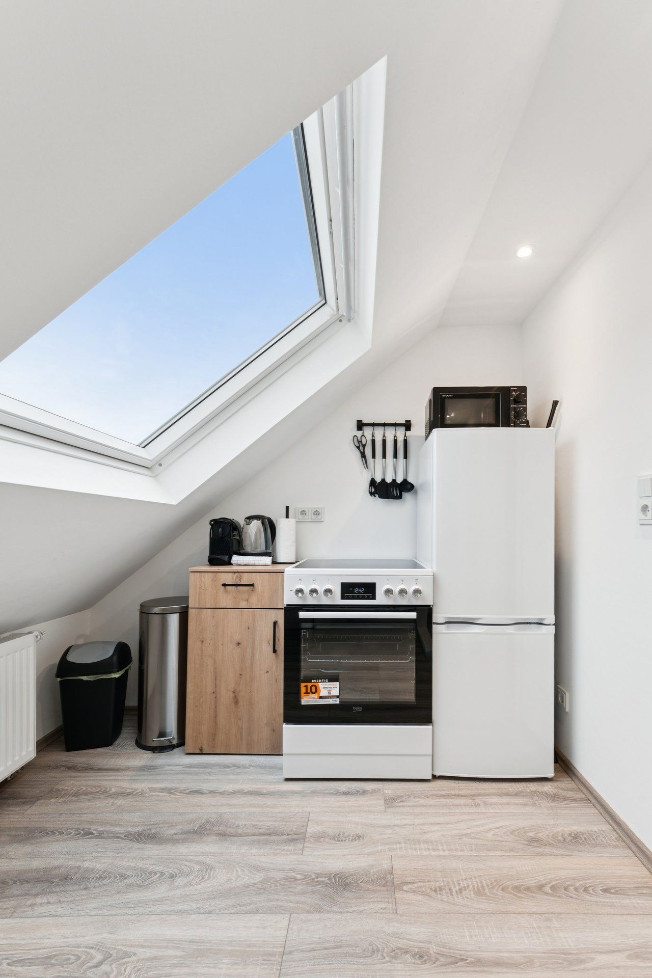 Une cuisine compacte dotée d’une lucarne, d’une cuisinière, d’un four à micro-ondes et d’un réfrigérateur.