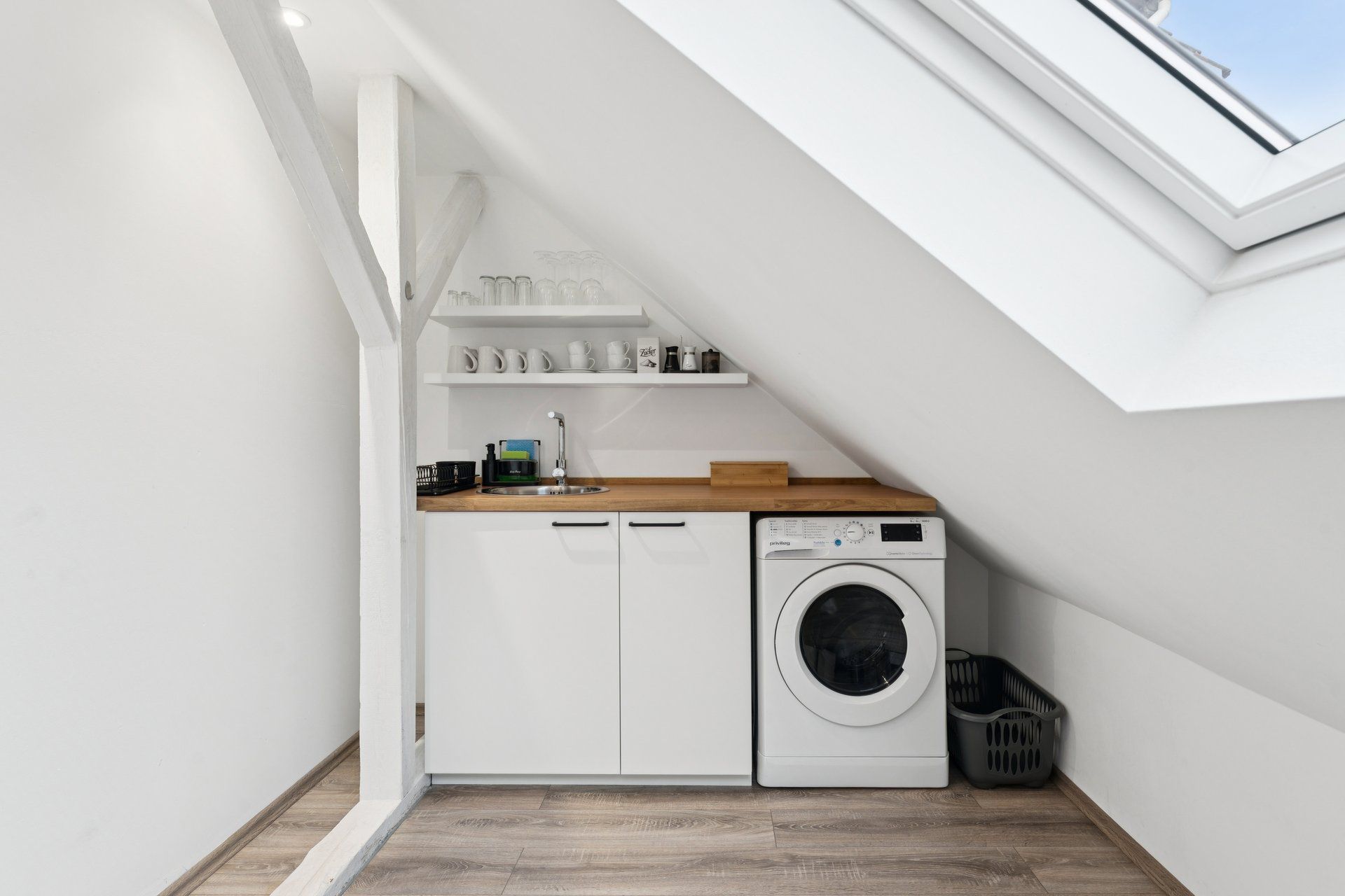 Une petite buanderie équipée d’un lave-linge, d’un évier et d’un étendoir.