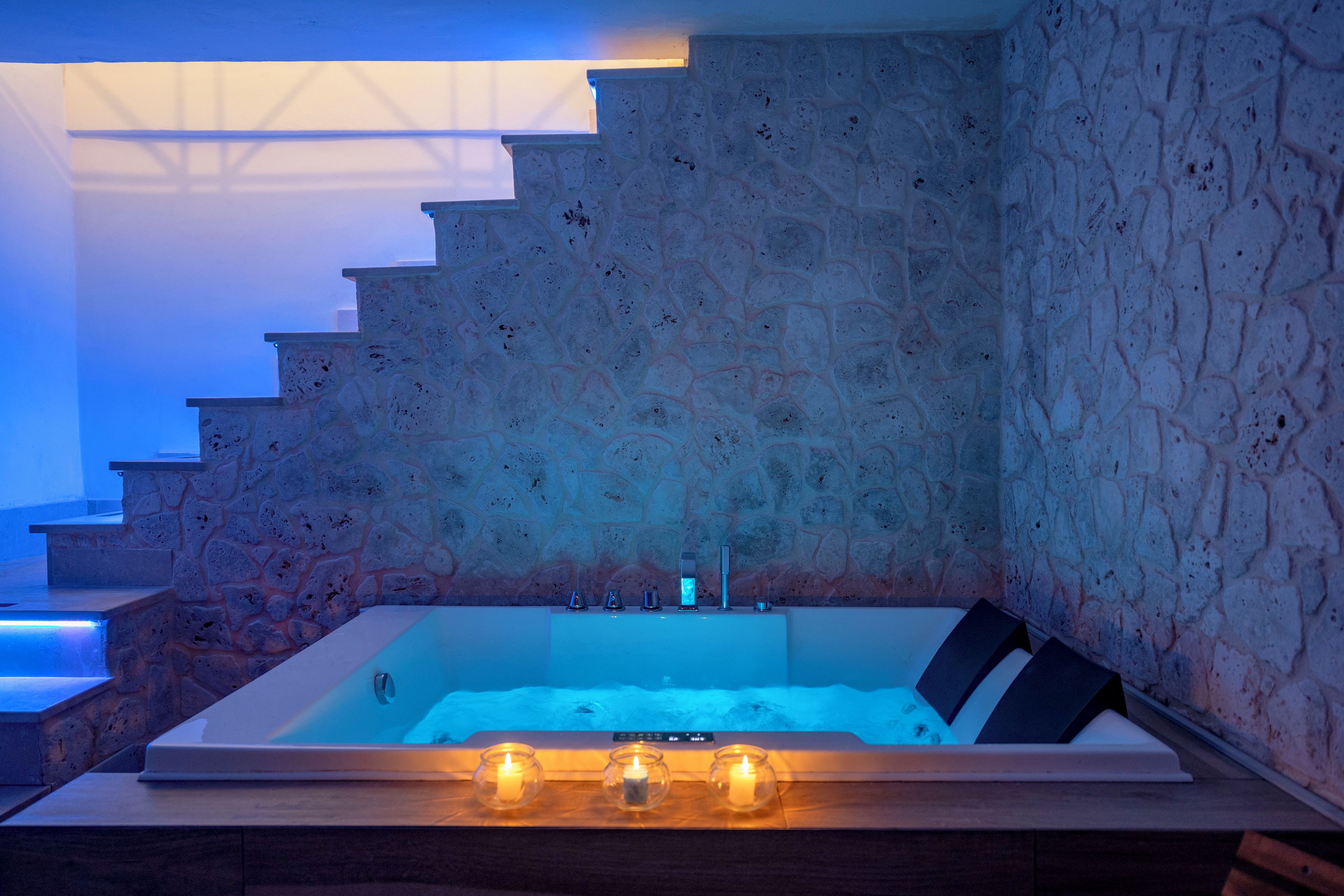 Un baño moderno con pared de piedra, una bañera y un conjunto de escaleras.