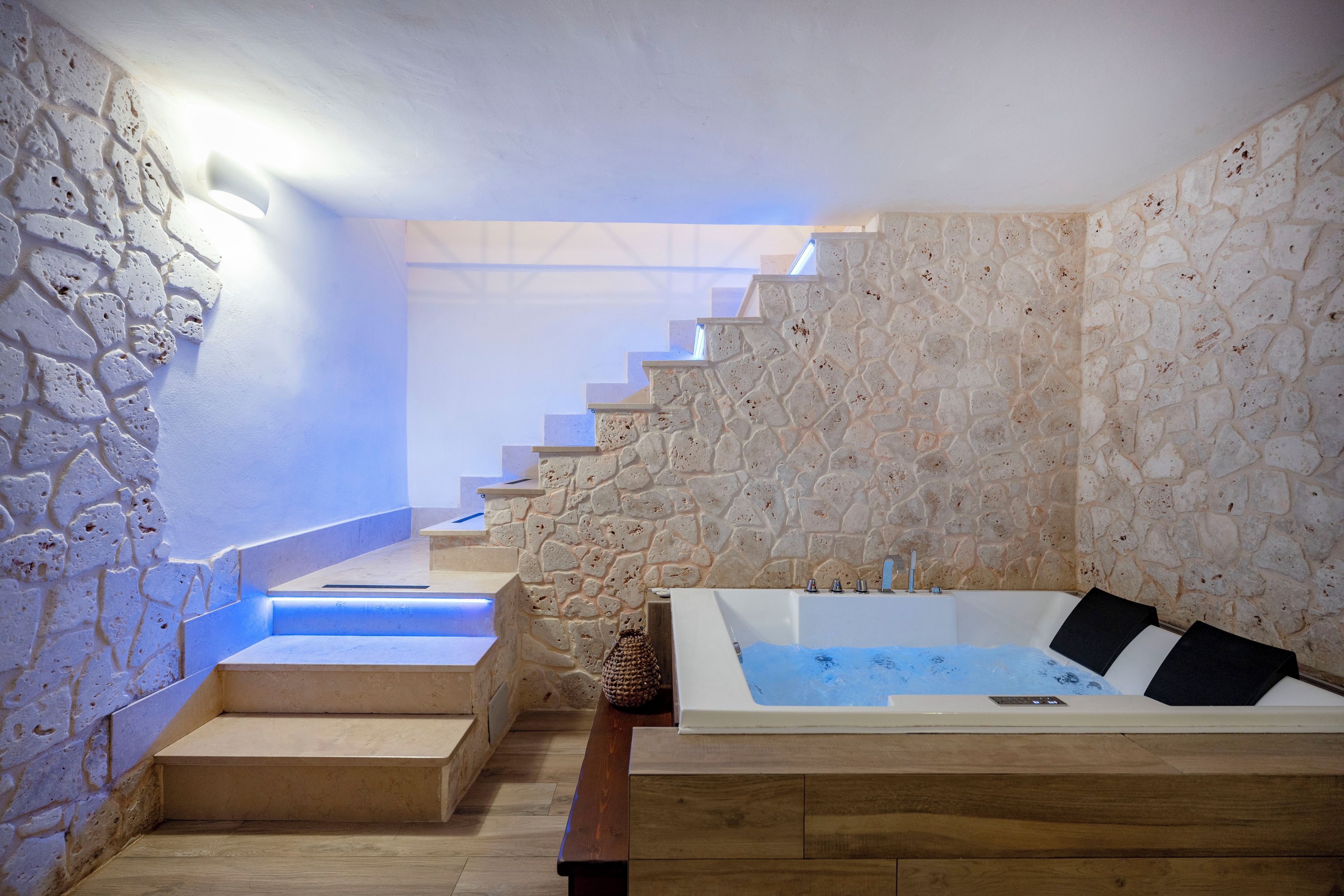 Un bagno con pareti in pietra, una panca di legno e una vasca da bagno.