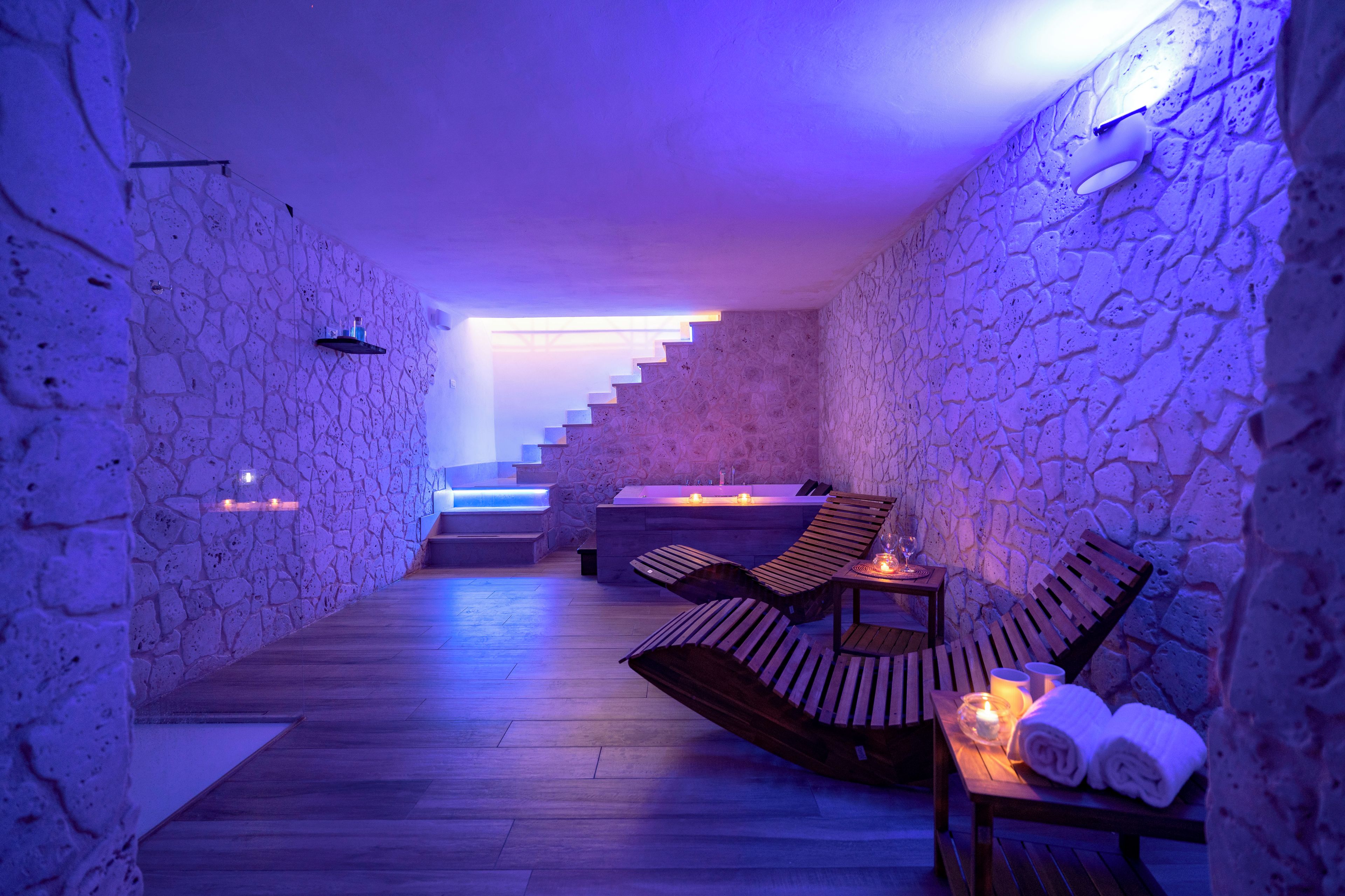 Una spa con pareti in pietra, pavimento in legno, una sauna e poltrone relax.