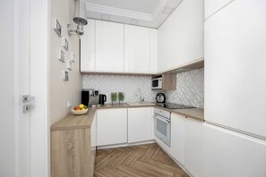 A modern kitchen with white cabinets, a wooden countertop, a microwave, a coffee machine, and a fruit bowl. - Kielce | Warszawska 218E | Spacious Apartment | Workspace (Kielce)