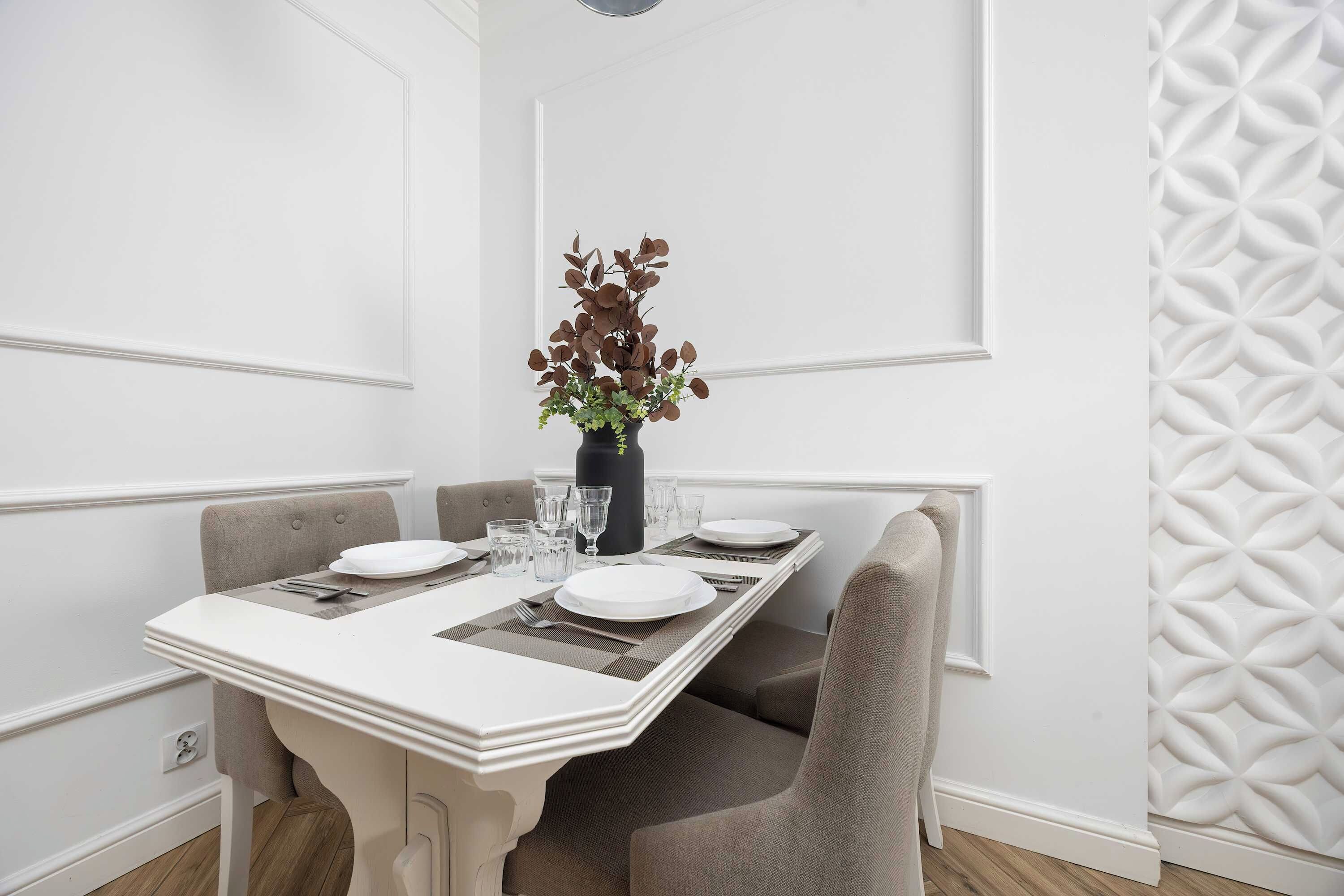A dining area with a white table set for two, including plates, glasses, and cutlery.