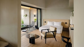Habitació d'hotel moderna amb un llit, dues cadires, una taula petita i vista a l'exterior.