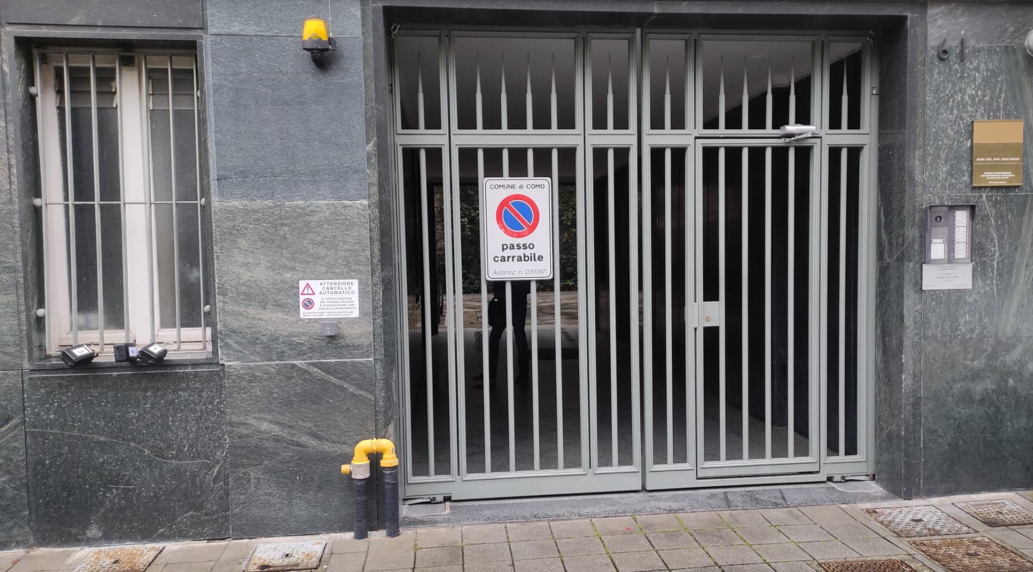 Ein verschlossener Eingangsbereich mit einem Verbotsschild, einem Warnschild und einem Schild mit der Hausnummer.