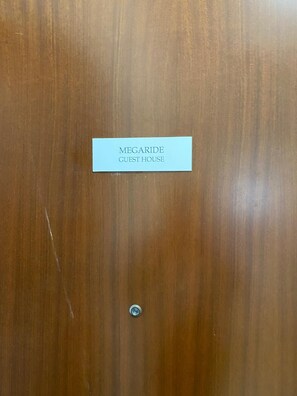 Una puerta de madera con una etiqueta que dice 'MEGARIDE GUEST HOUSE'.