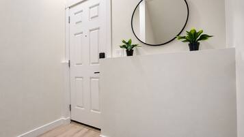 A hallway with a white door, a round mirror, and two potted plants.