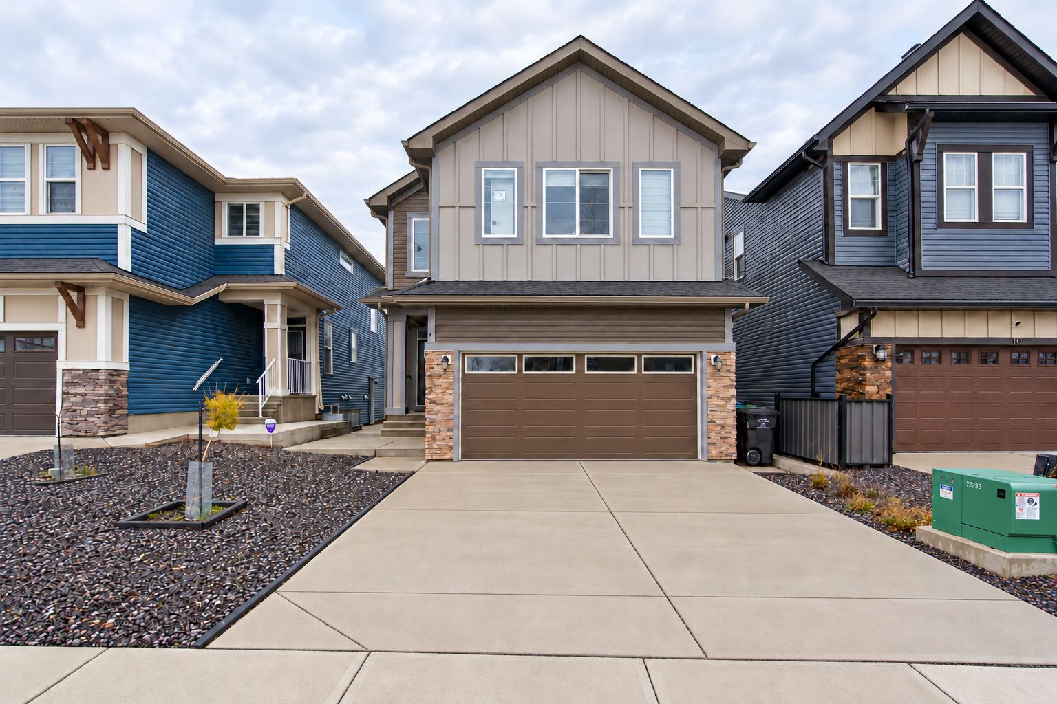 A residential area with modern two-story houses, a central driveway, and a well-maintained landscape.