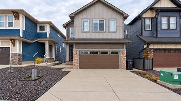 A residential area with modern two-story houses, a central driveway, and a well-maintained landscape.
