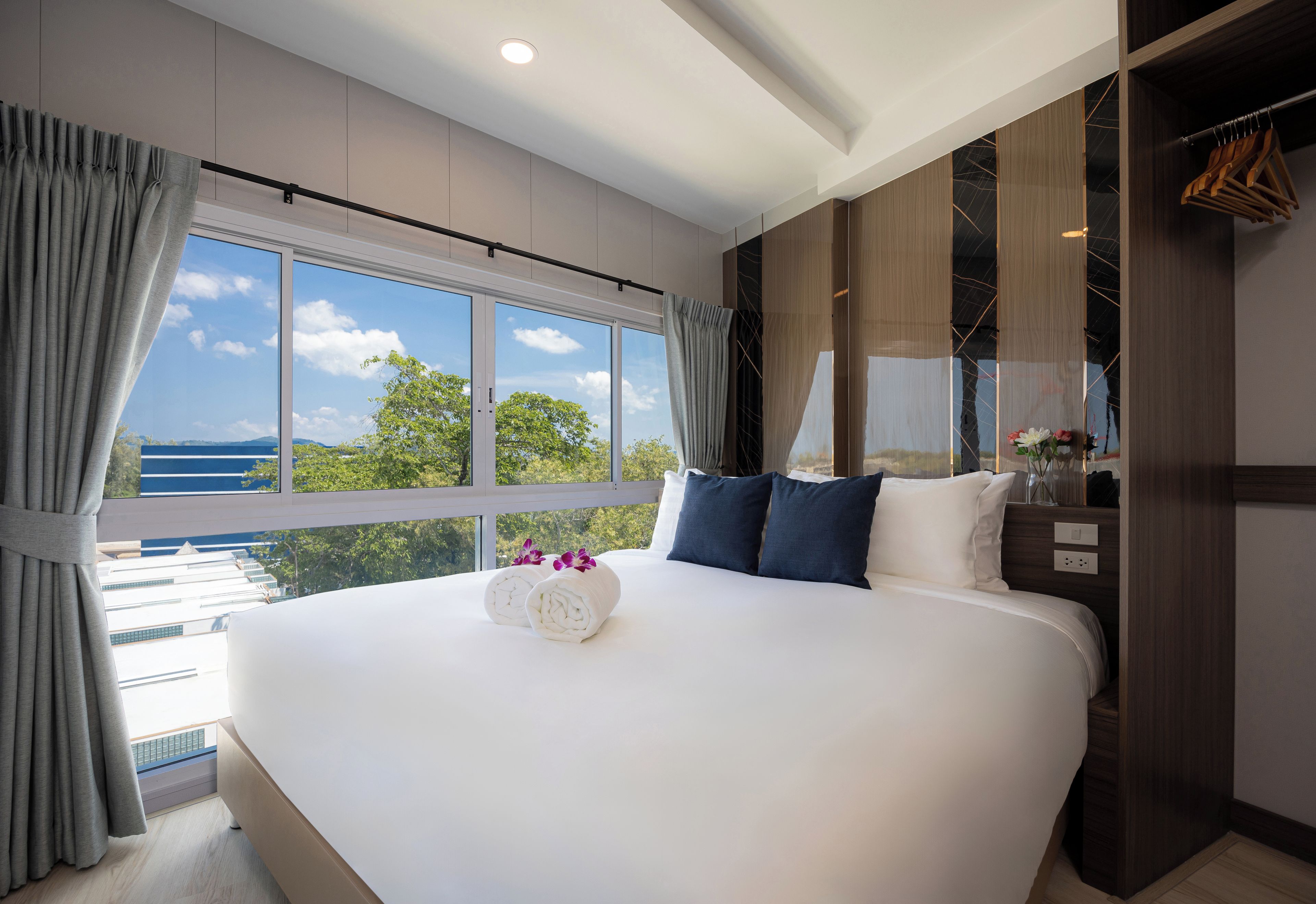 Une chambre d’hôtel avec un grand lit, une vue sur la mer et une armoire avec un miroir.