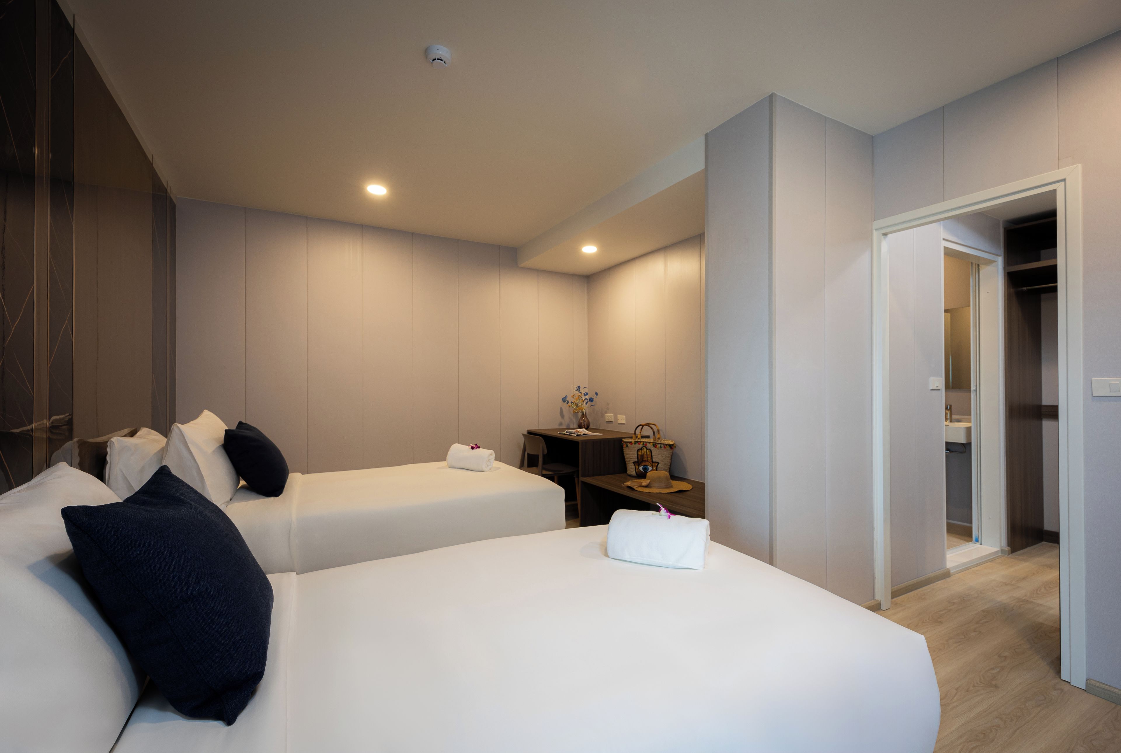 A hotel room with two beds, a desk, a chair, and a wardrobe.