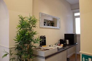 Un área de recepción con mostrador, un espejo, un cartel, una planta y un ventanal.